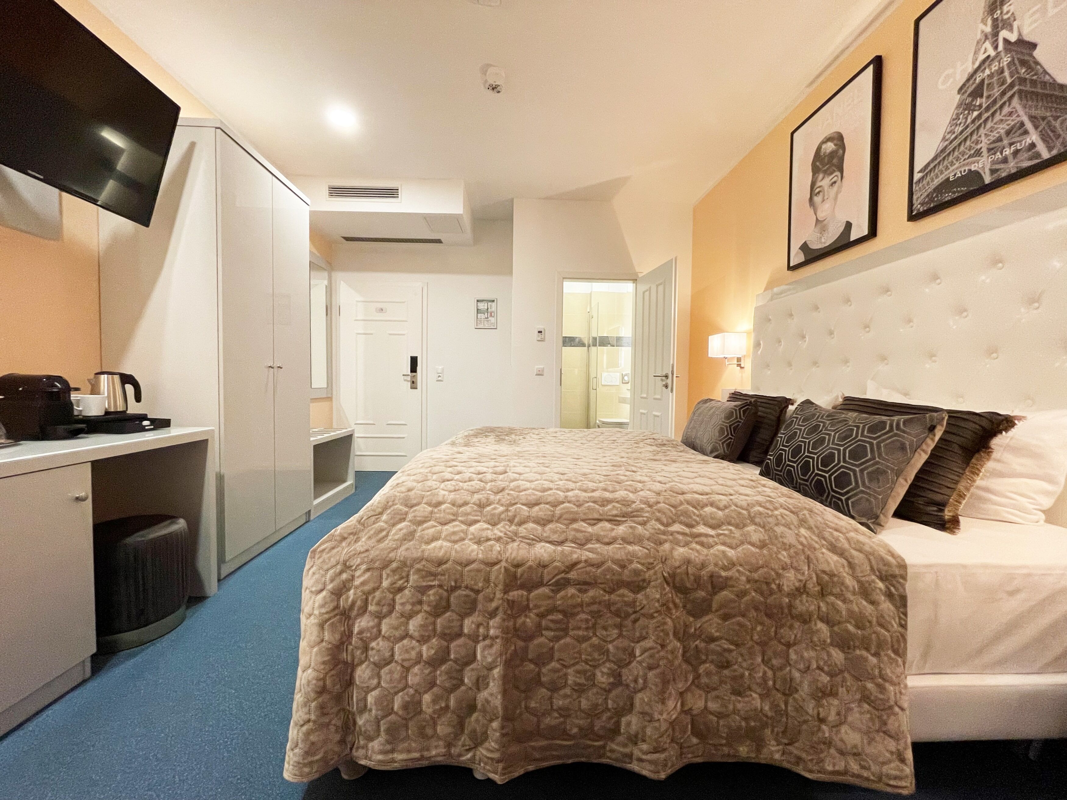 Een hotelkamer met een groot bed, een bureau, een televisie en een badkamer zichtbaar door een open deur.
