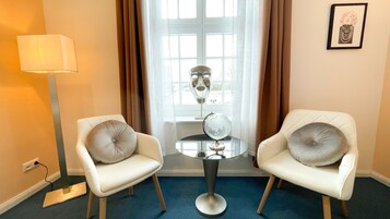 Una habitación con dos sillones blancos, una mesita redonda, un globo terráqueo y un cuadro en la pared.