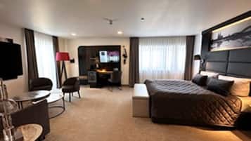 Una camera d'albergo moderna con un letto grande, una scrivania con un computer, una sedia e una TV.