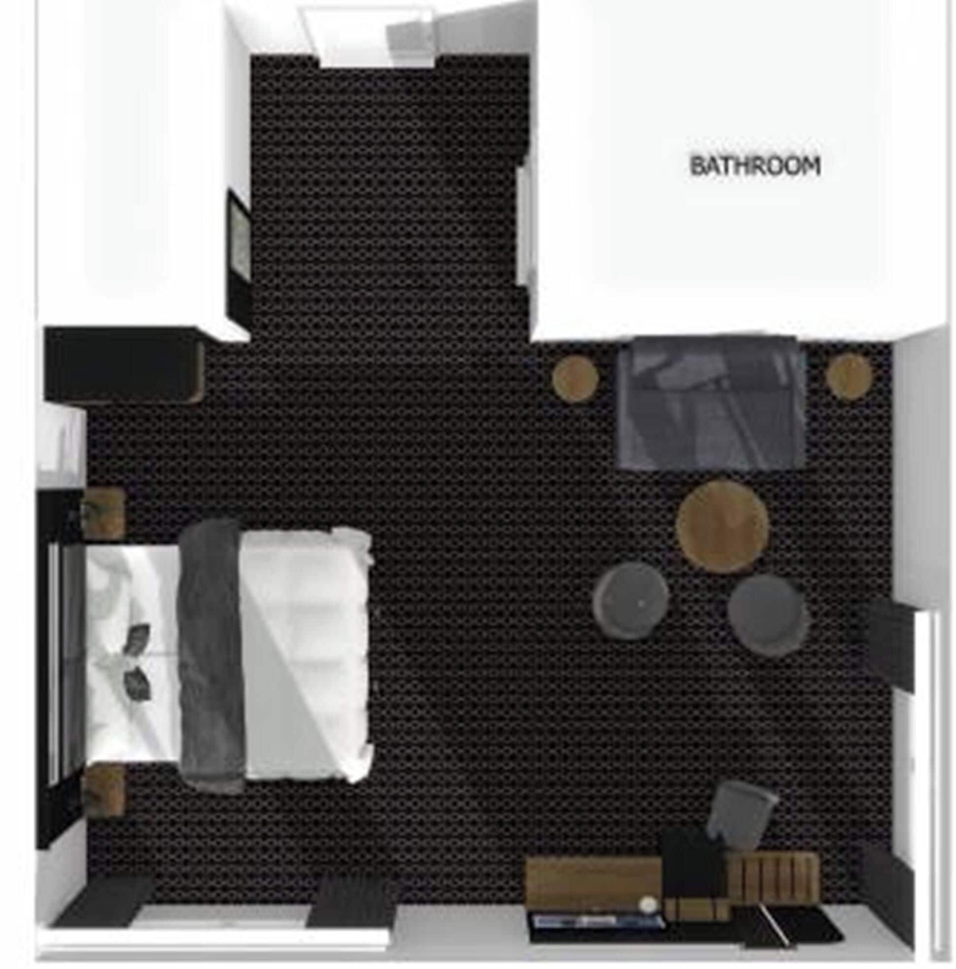 A hotel room with a bed, a small seating area, a bedside table, a lamp, and a bathroom.