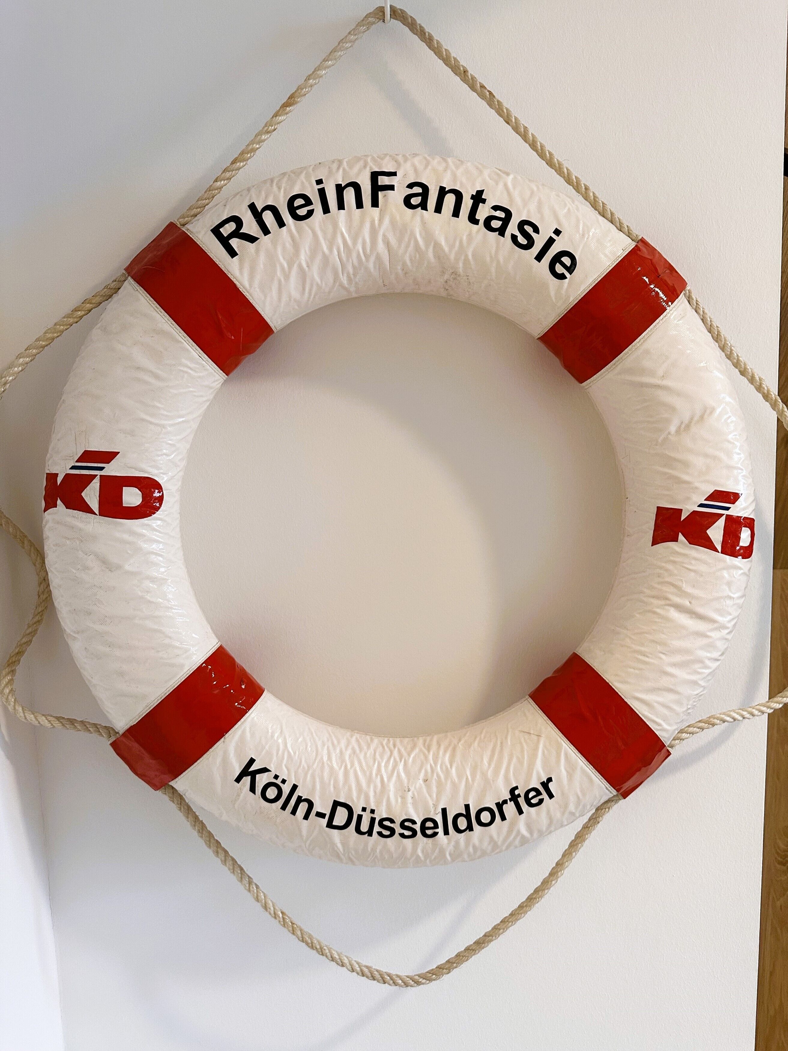 Een witte reddingsboei met rode accenten en de tekst 'RheinFantasie' en 'Köln-Düsseldorfer'.