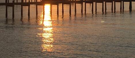A sunset over a calm body of water with a dock extending into the water.