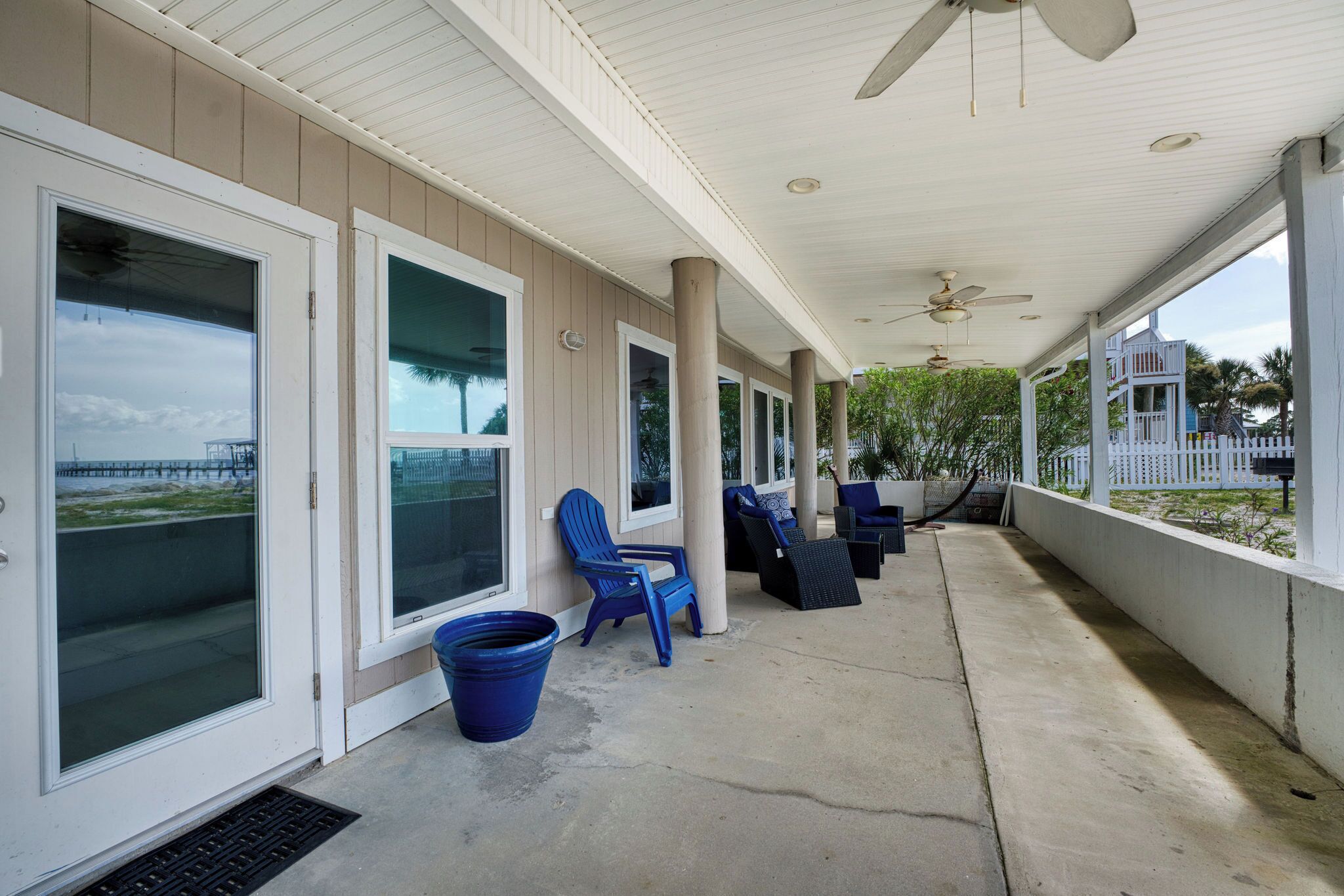 A covered porch with large windows, a ceiling fan, and outdoor seating.