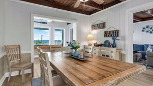 Un comedor con una mesa y sillas de madera, vistas al exterior y una lámpara sobre la mesa.