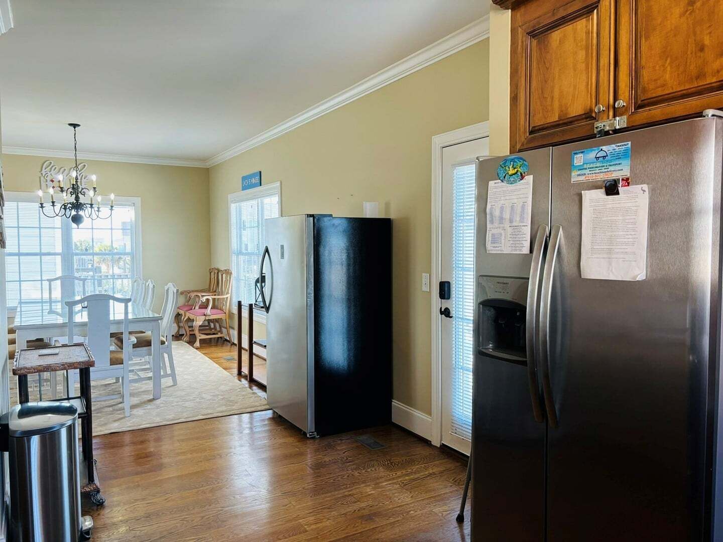 Una cocina equipada con refrigerador, dispensador de agua y comedor con mesa y sillas.