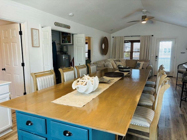 A dining area with a wooden table, blue cabinetry, and a kitchen in the background.