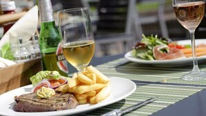 Spisebord med steak, pommes frites og salat, samt en vinflaske og et vinglas.