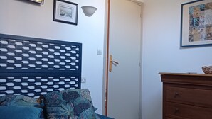 Een slaapkamer met een bed, een dressoir, een deur en wandlampen.