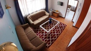 A living room with a sofa, a coffee table, and a TV. - Stay.Plus Hurlingham B&B Suite (Nairobi)