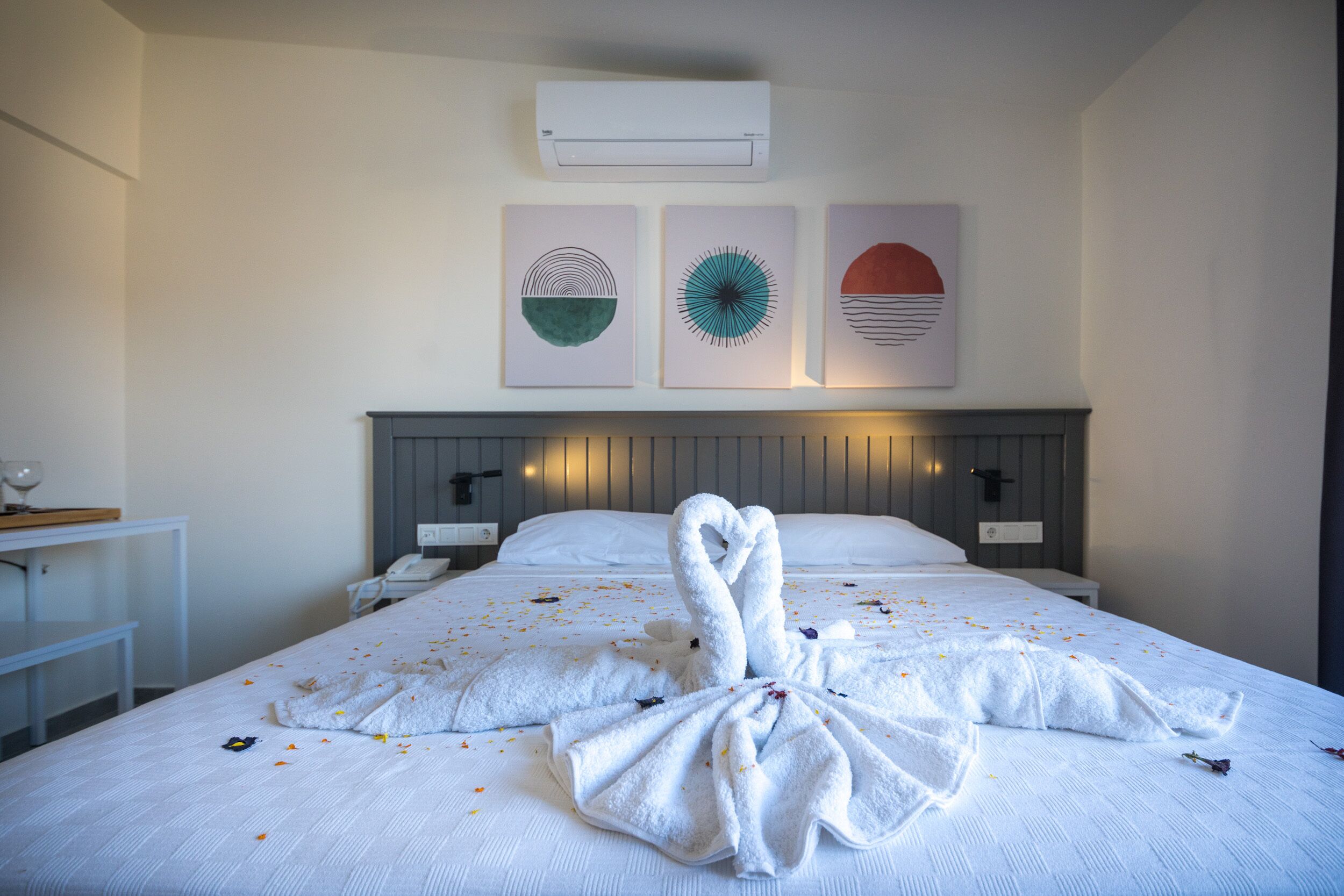 Quarto de hotel com cama, mesa de cabeceira e ar condicionado fixado na parede.