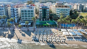 Et kysthotel med flere etager, et poolområde og siddepladser ved stranden.