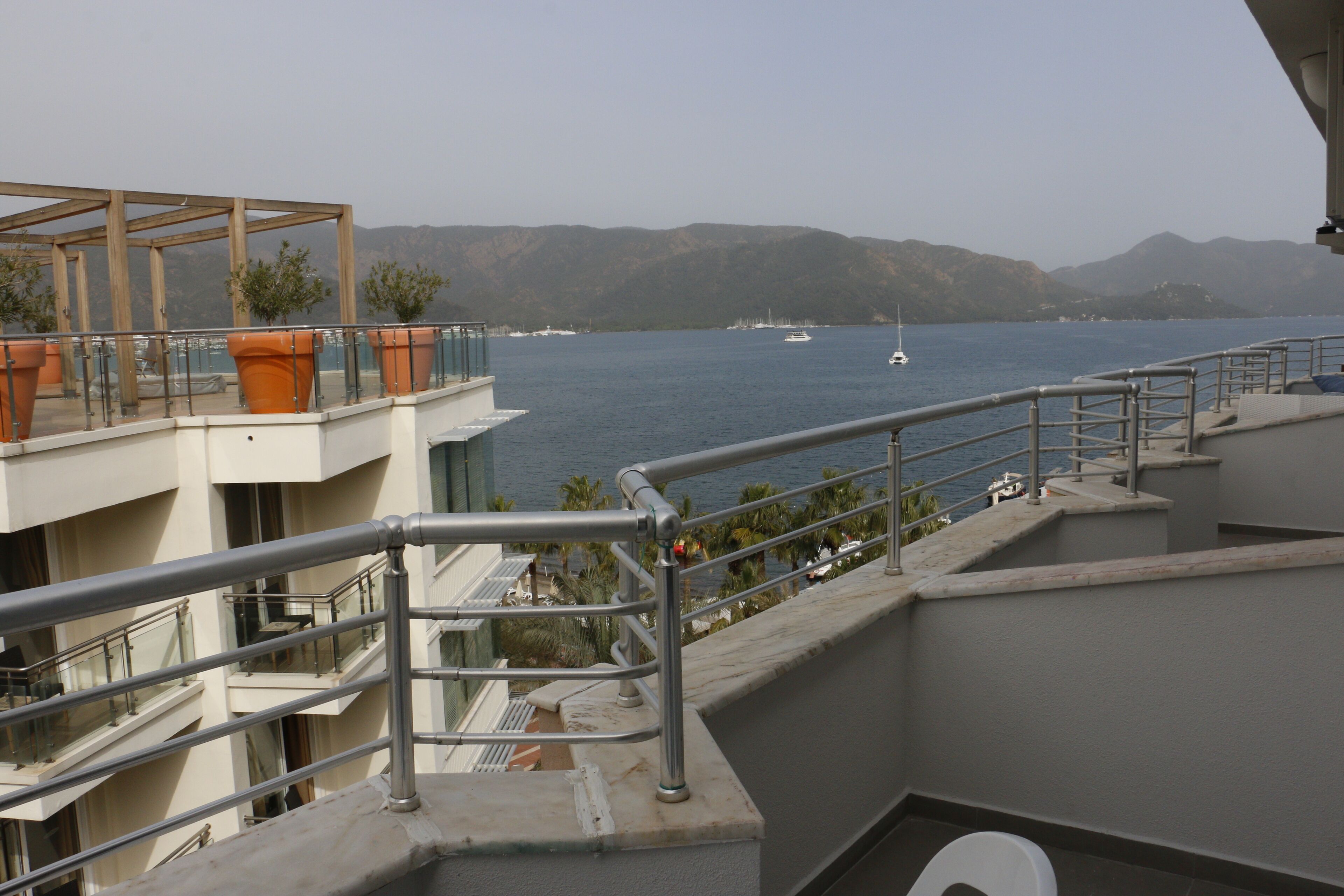 A balcony with a view of the sea, potted plants, and a railing.