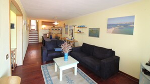 A living room with a sofa, a coffee table, and a rug. There is a staircase leading to another room. - Tanca Manna three bedrooms apartment 3 bedrooms 2 bathrooms large sea view (Cannigione)