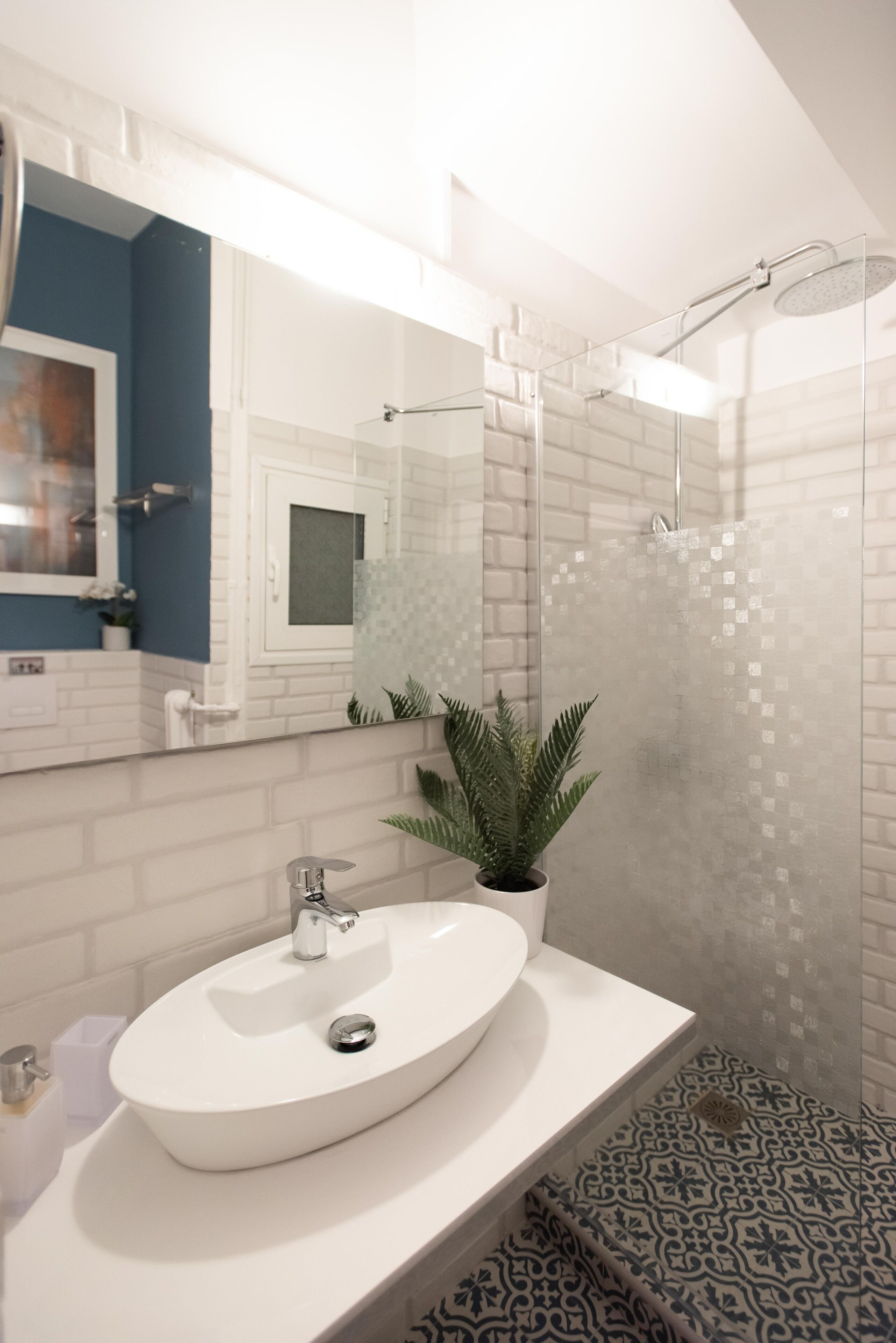 Une salle de bain moderne avec un lavabo blanc, un miroir et un espace douche.