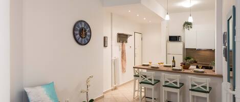 A modern kitchen with a bar area, white cabinets, and a clock on the wall.