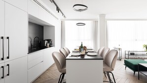 A modern kitchen with white cabinets, a black countertop, and a dining area with a table set for four. - Modern and Central 2BD Apartment in TLV (Tel Aviv)