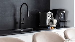 A modern kitchen with a black countertop, a coffee machine, and a sink. - Modern and Central 2BD Apartment in TLV (Tel Aviv)