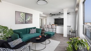 A modern living room with a green sofa, black and white patterned cushions, a round coffee table, and a potted plant. - Modern and Central 2BD Apartment in TLV (Tel Aviv)