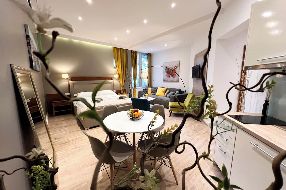 Ein modernes Hotelzimmer mit Bett, einer Couch, einem Esstisch mit Stühlen und einer Küchenzeile.