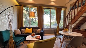 A modern living room with a sofa, coffee table, and chairs, a dining table with a vase, and a staircase. - Adriatic Resort Apartments (Dubrovnik)