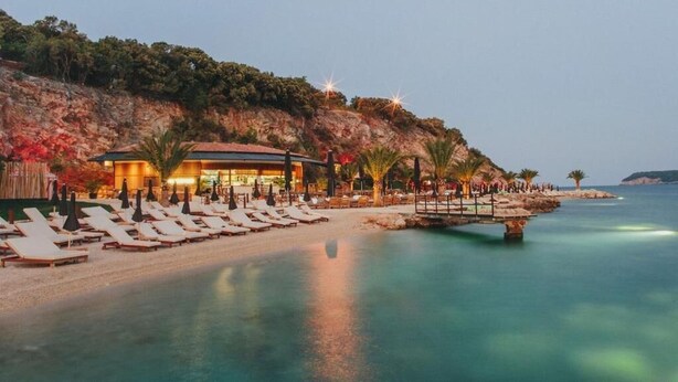 A beachside hotel with sun loungers, a pool, and a building with a red roof. - Adriatic Resort Apartments (Dubrovnik)