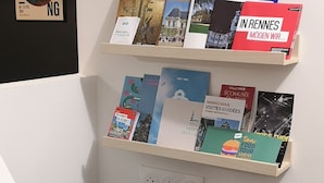 Et tekøkken med kaffemaskine, en stikkontakt og to hylder med rejseguide og bøger.