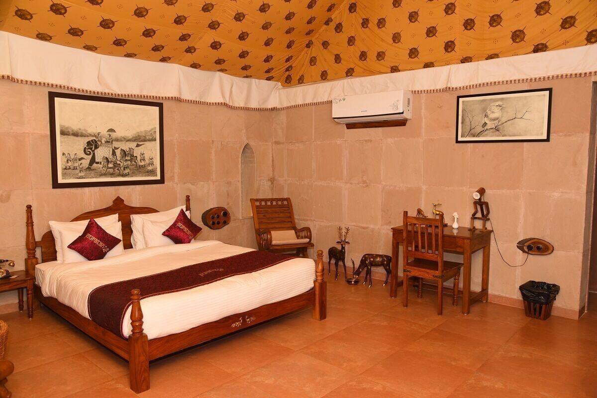 Un dormitorio con una cama de madera, un escritorio, sillas y dos cuadros en la pared.