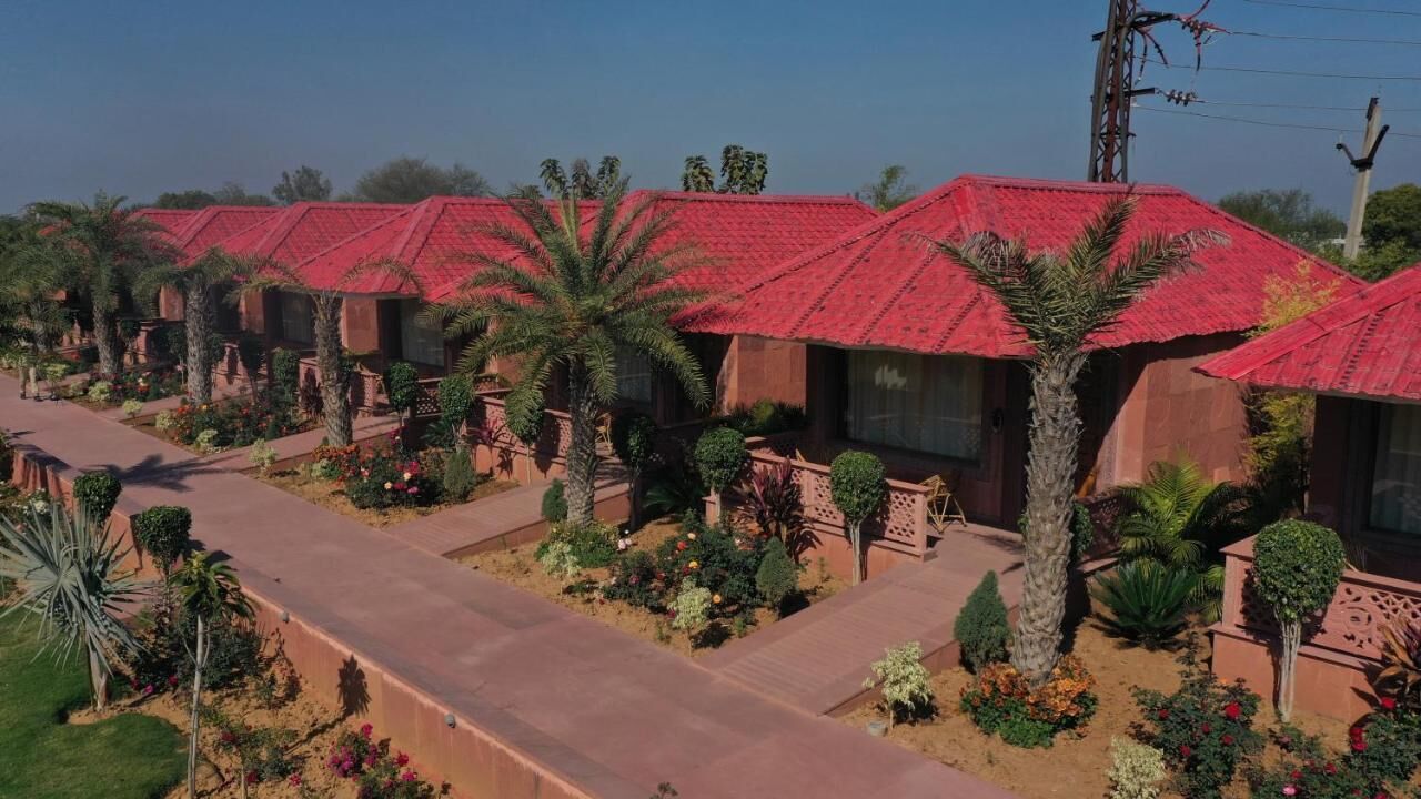Eine Reihe von bungalows mit roten Dächern, umgeben von angelegten Gärten und Palmen.