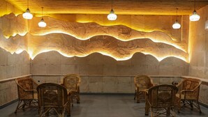 Una habitación con un diseño único de techo ondulado, sillas de mimbre dispuestas en semicírculo e iluminación colgante.