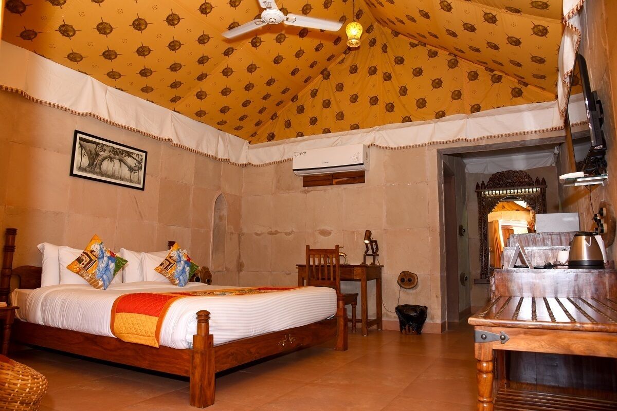 A room with a bed, a desk, a chair, a ceiling fan, and an air conditioning unit.