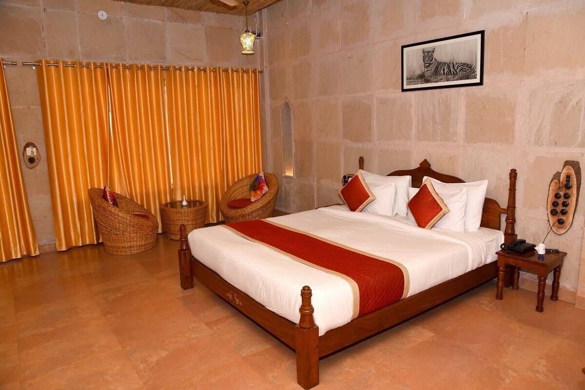 Un dormitorio con una cama de madera, una pared de piedra, un cuadro enmarcado y sillas de mimbre.