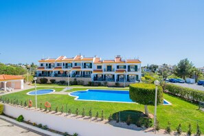 A multi-story hotel with a swimming pool, a well-maintained lawn, and a parking area. - Lily Fabulous 1 Bed Apt with Roof Terrace & Pool (Carvoeiro)
