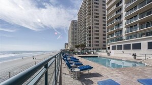 Un hôtel situé en bord de mer, doté d’une piscine, d’une plage et entouré de bâtiments de grande hauteur.