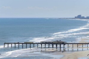 A pier extending into the ocean with a building at the end, a beach in the background, and a distant city skyline. - #606 Dimucci TT (Daytona Beach Shores)