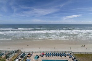 Une plage avec vue sur l’océan, un espace clos avec des chaises longues et une piscine.