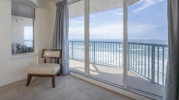 Une pièce dotée d’une grande porte-fenêtre coulissante donnant sur un balcon avec vue sur la plage.