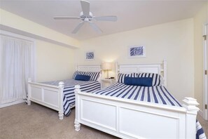 Ein Schlafzimmer mit zwei Einzelbetten, einem Deckenventilator und zwei Nachttischen mit Lampen.