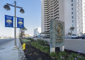 Un immeuble portant une enseigne indiquant « Twin Towers » et deux banderoles pour « Daytona Beach Shores » avec le slogan « La vie est plus belle ici ».