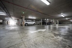 A multi-level parking garage with concrete floors and pillars, featuring a white arrow indicating direction. - #606 Dimucci TT (Daytona Beach Shores)