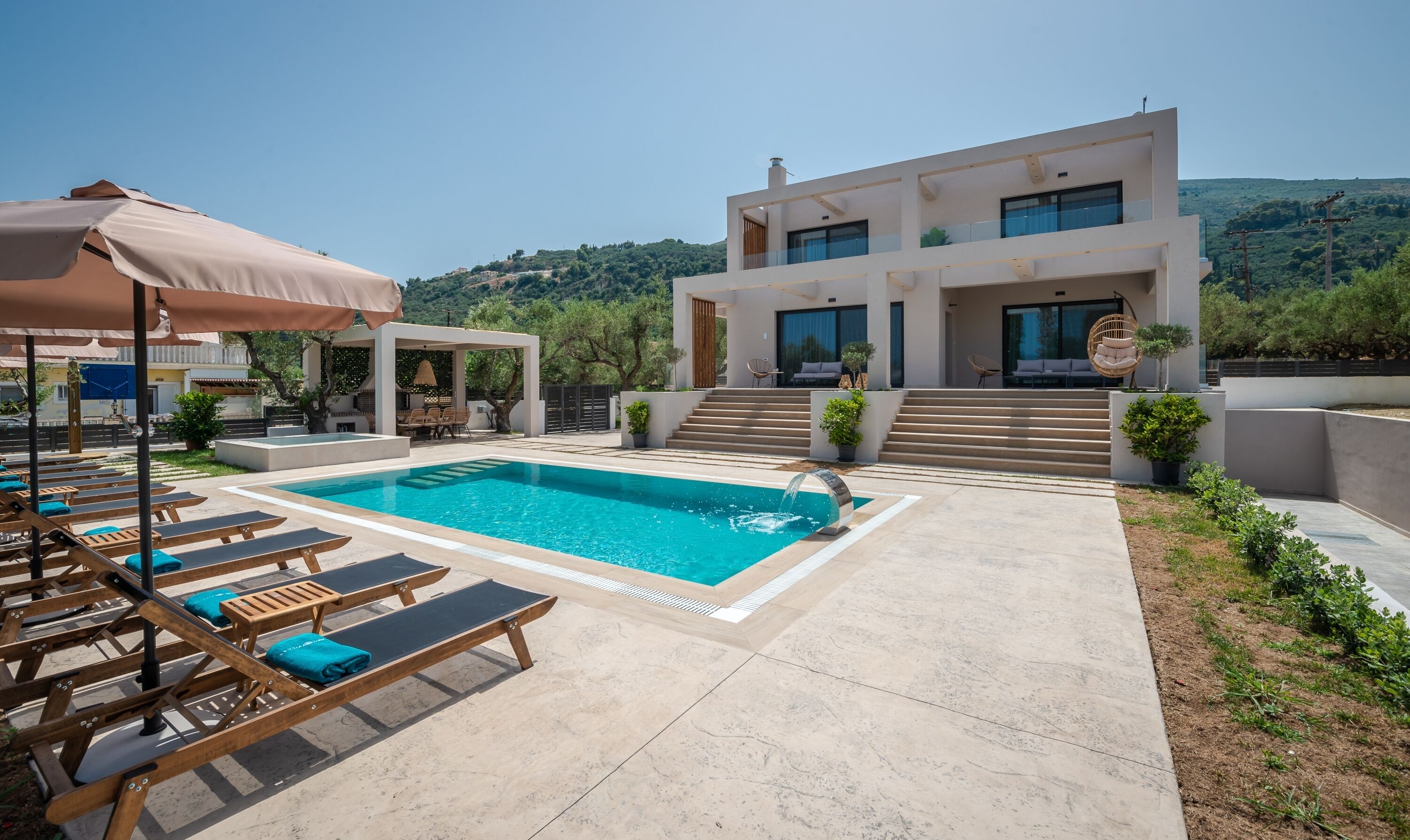 A modern pool area with lounge chairs and a clear view of a hillside.
