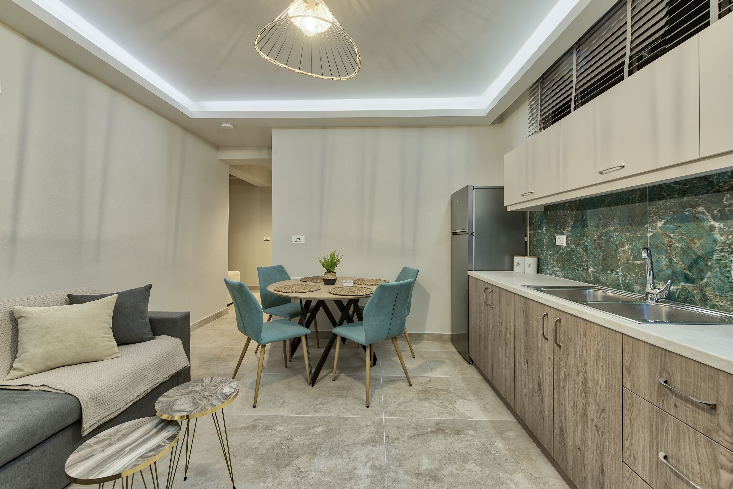 Een moderne keuken met een marmeren spatwand, een eethoek met een ronde tafel en stoelen, en een inbouwoven.
