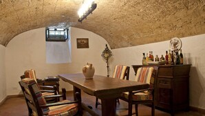 A rustic dining room with a wooden table, striped chairs, and a cabinet with bottles. - 1800 Tuscan villa - walking distance from a pretty village (Fornoli)