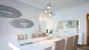 A modern dining area with a white table, six chairs, and a chandelier. - Villa Alfazema | 5 Bedrooms | Quiet Area | Albufeira (Albufeira)