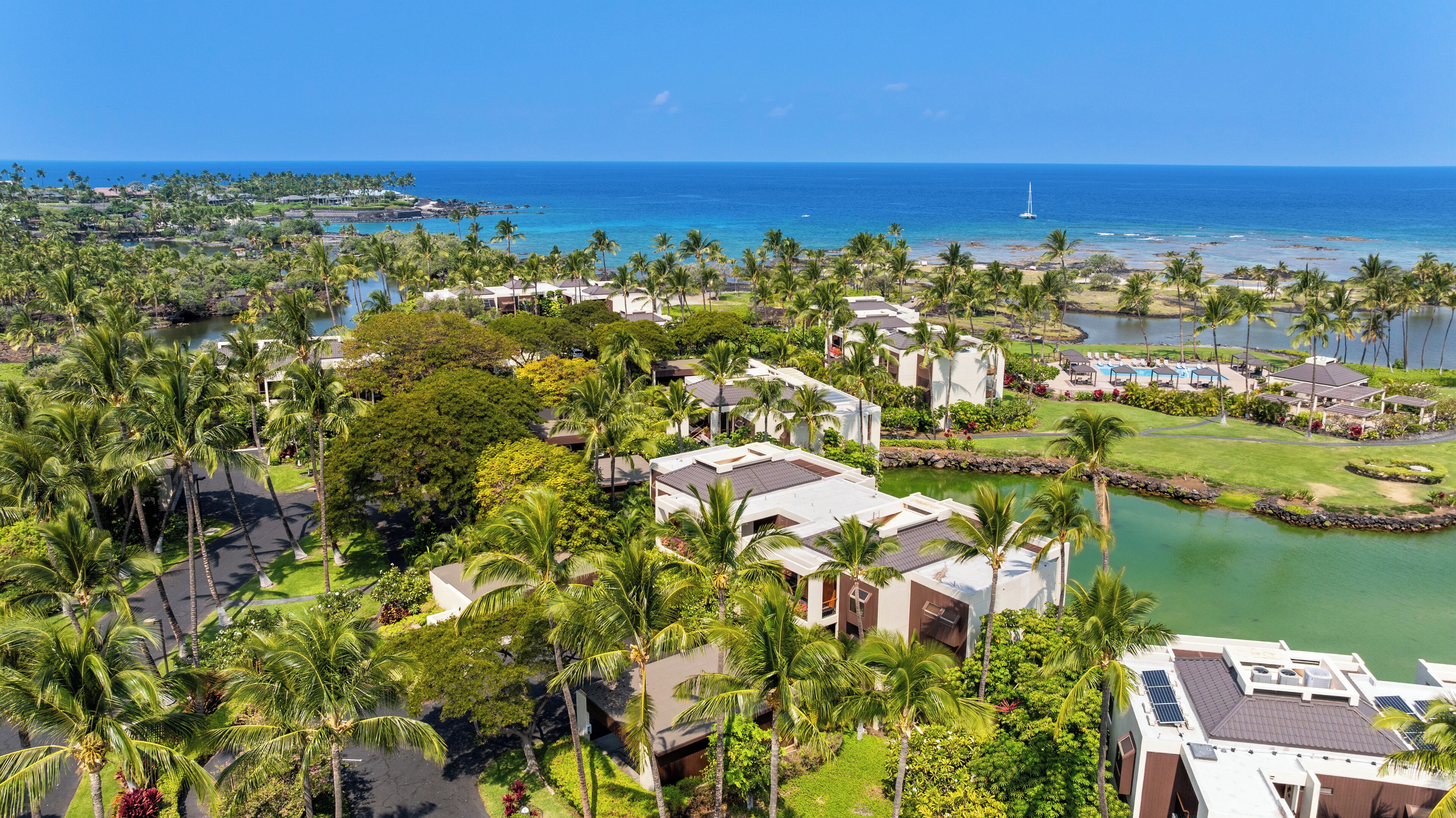 A resort with multiple buildings, a pool, and a view of the ocean.