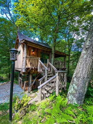 A wooden treehouse with a staircase leading up to it, surrounded by lush greenery.