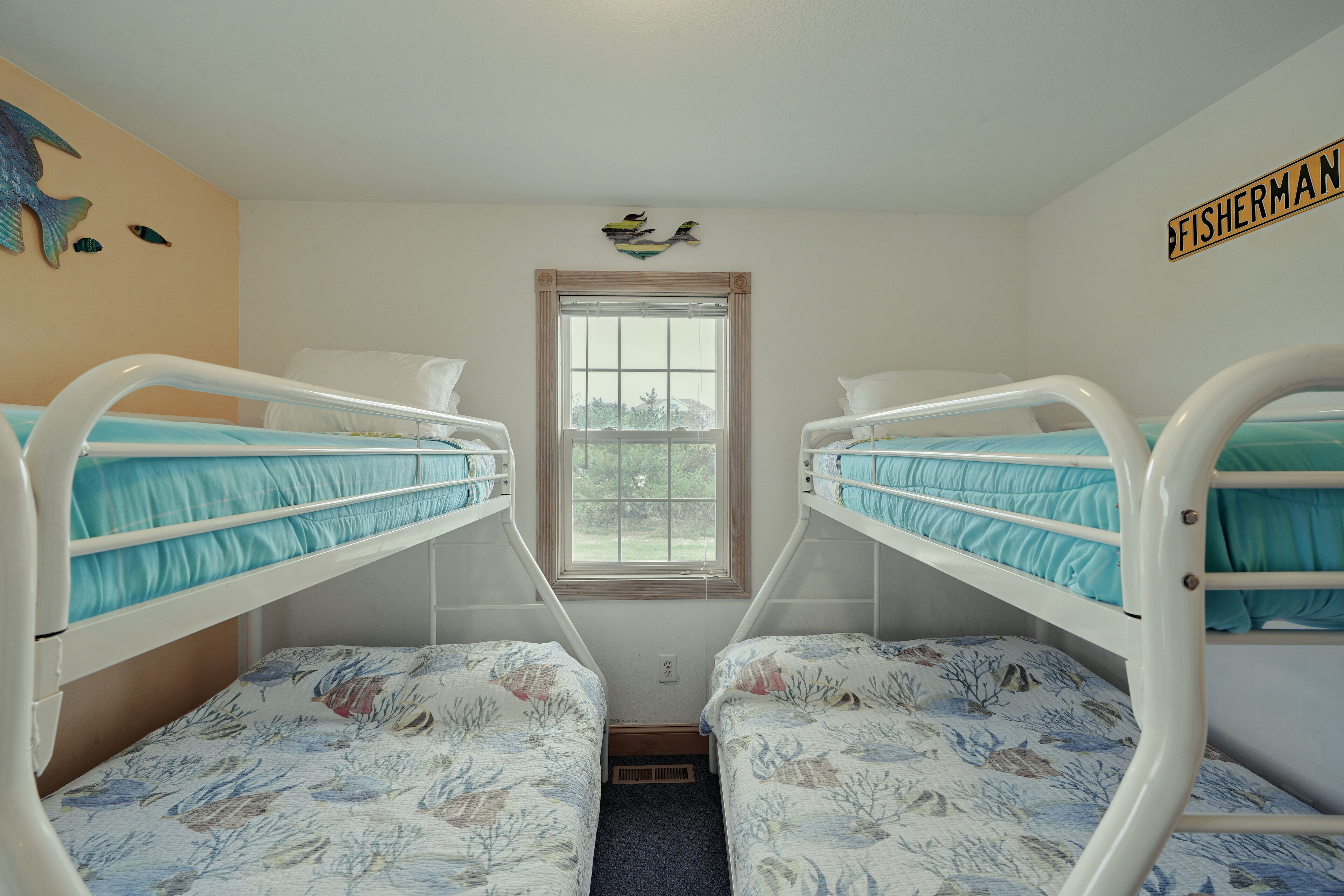 A room with bunk beds, a window, and a wall decoration.