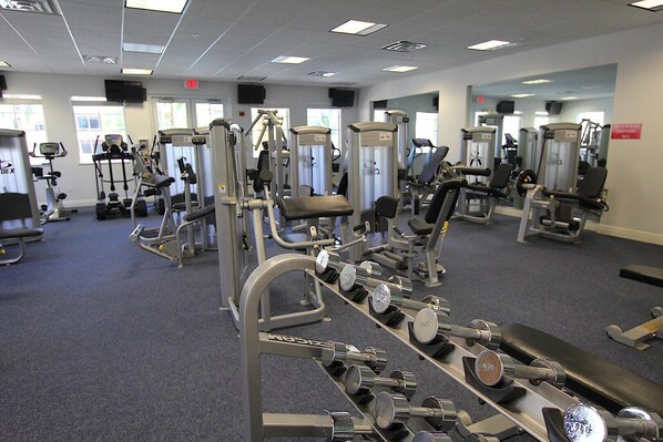 Un gimnasio con diversas máquinas de ejercicio, incluyendo cintas de correr, máquinas de pesas y pesas libres.