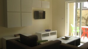 A living room with a sofa, a coffee table, and a TV mounted on the wall. - Seaside (200m to beach), bright, spacious ground floor apartment, Les Dunes S+2 (Akouda)