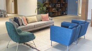 Un soggiorno moderno con un divano grigio, poltrone color petrolio e blu, e un tappeto decorato.