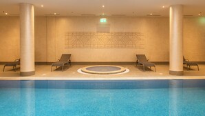 Piscina con lettini e un design di parete geometrico.